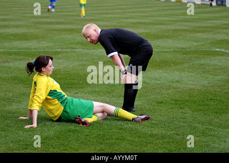 Referee attending women`s football player on ground, UK Stock Photo